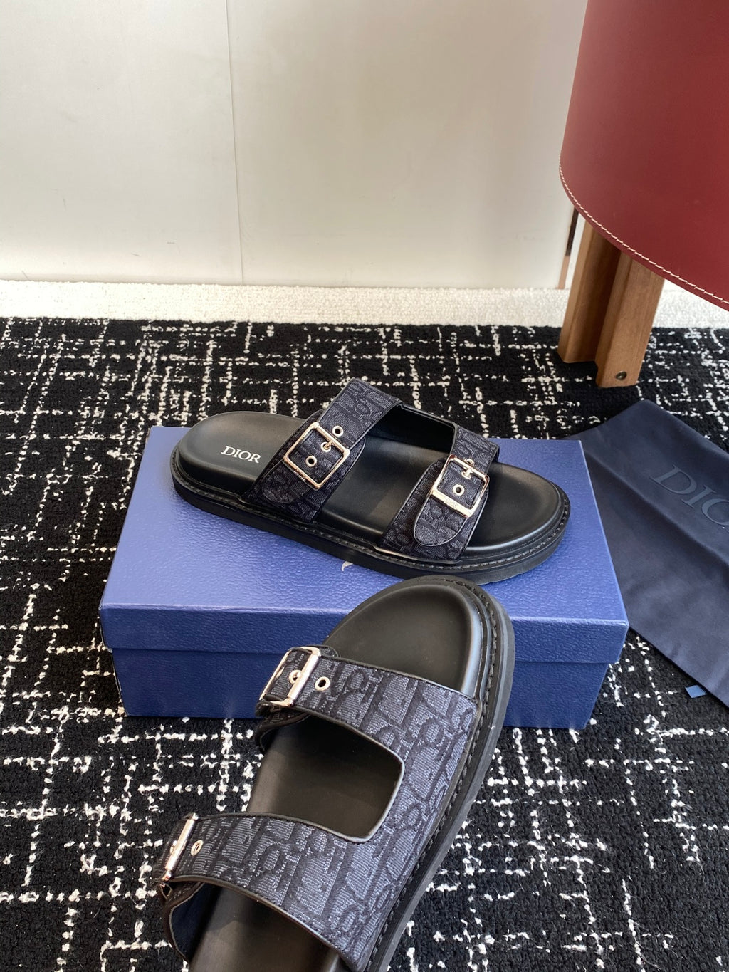 Dior sandals with dark blue patterned straps and silver buckles, shown on blue box
