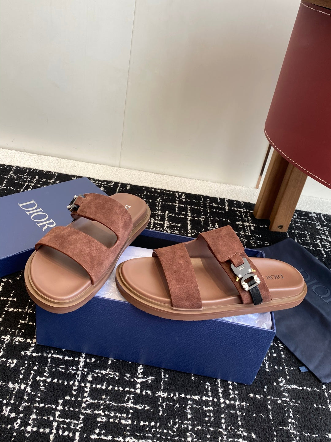 Dior slide sandals in brown suede with two straps and metal buckles, angled view