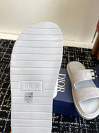 Dior sandal outsole with tread, paired with light gray suede slide upper and silver buckle