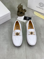 Pair of white slip-on loafers with gold-tone buckle across the front