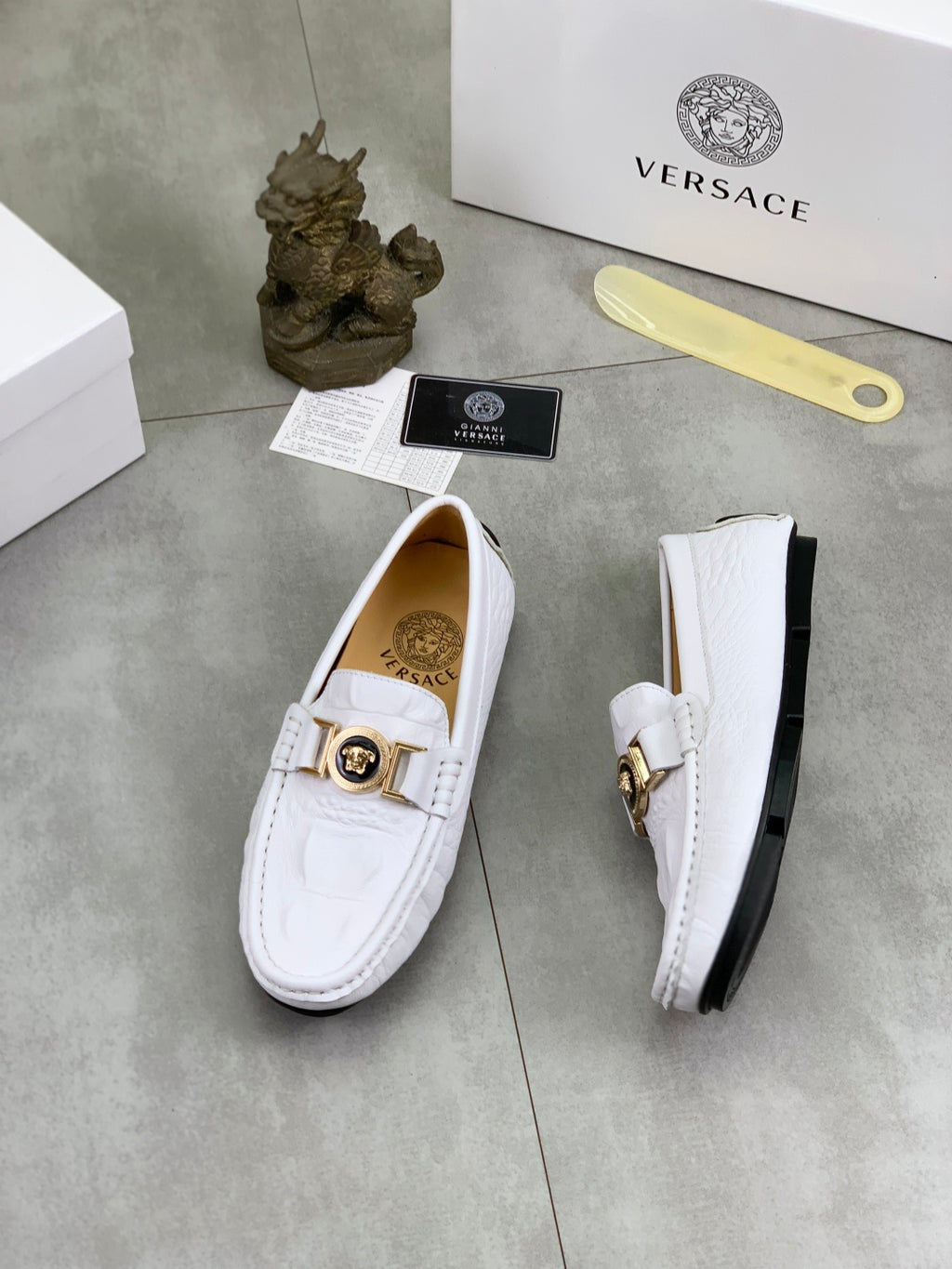 White slip-on loafers, one side view showing gold buckle and black sole edge