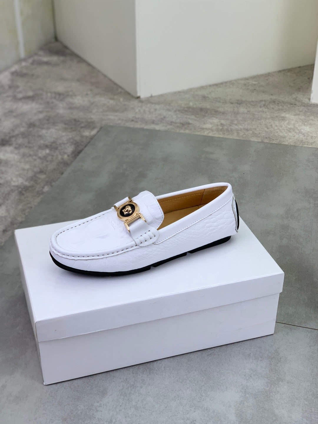 White slip-on loafer with gold buckle hardware on the front strap