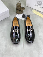 Pair of black patent leather loafers with metal emblem and slip-on design