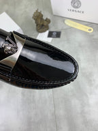 Black patent leather loafer side view with metal emblem and glossy finish