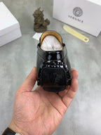 Black patent leather loafer back view with stitched detailing and logo panel