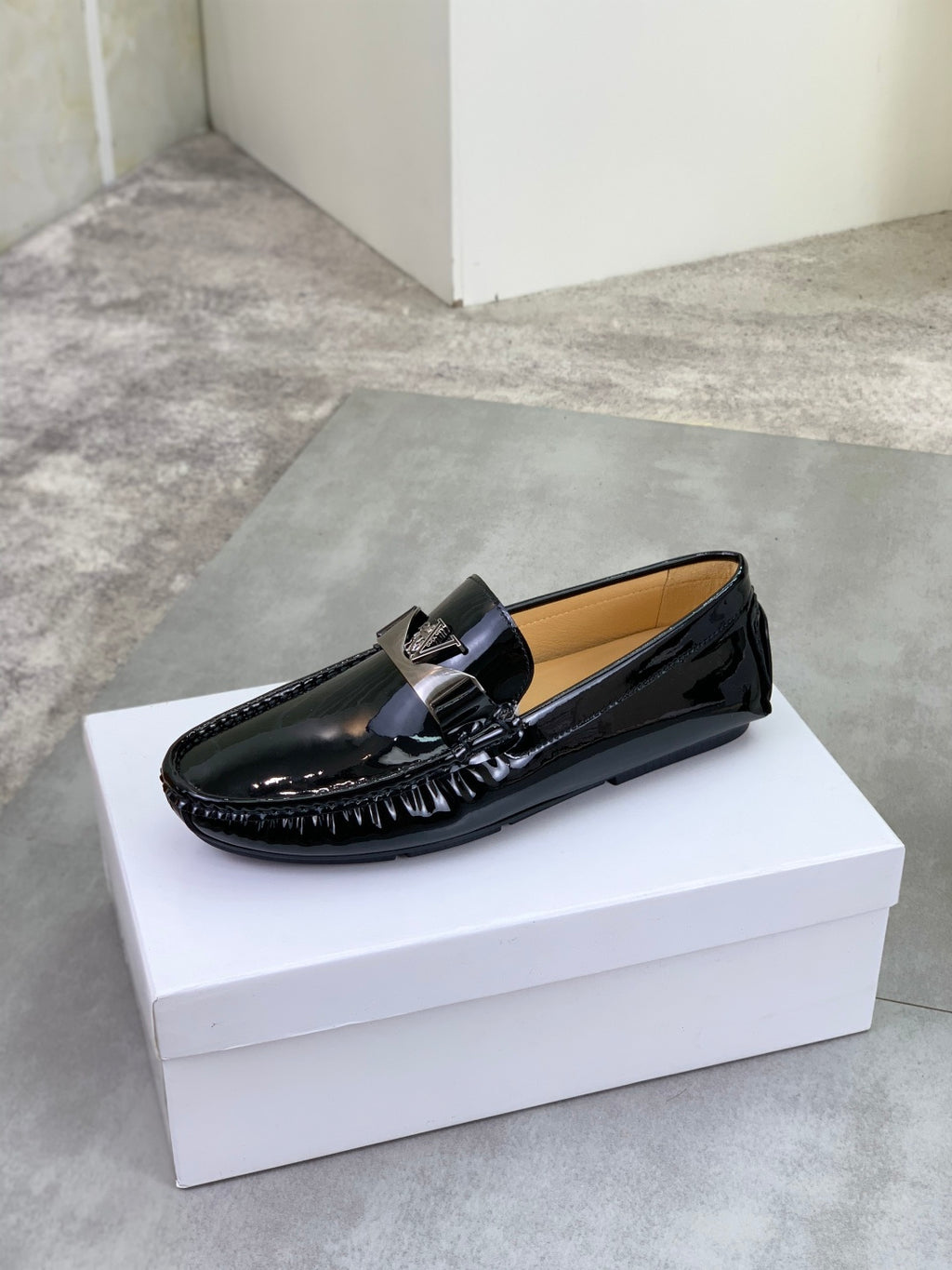 Black patent leather loafer with metal bar buckle and smooth moccasin stitching