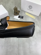 Black leather loafer showing tan interior lining and stitched strap