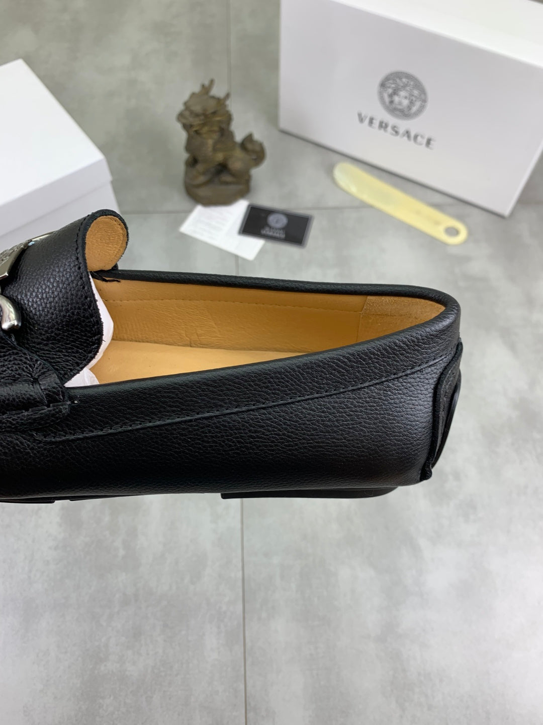 Black leather loafer showing tan interior lining and stitched strap