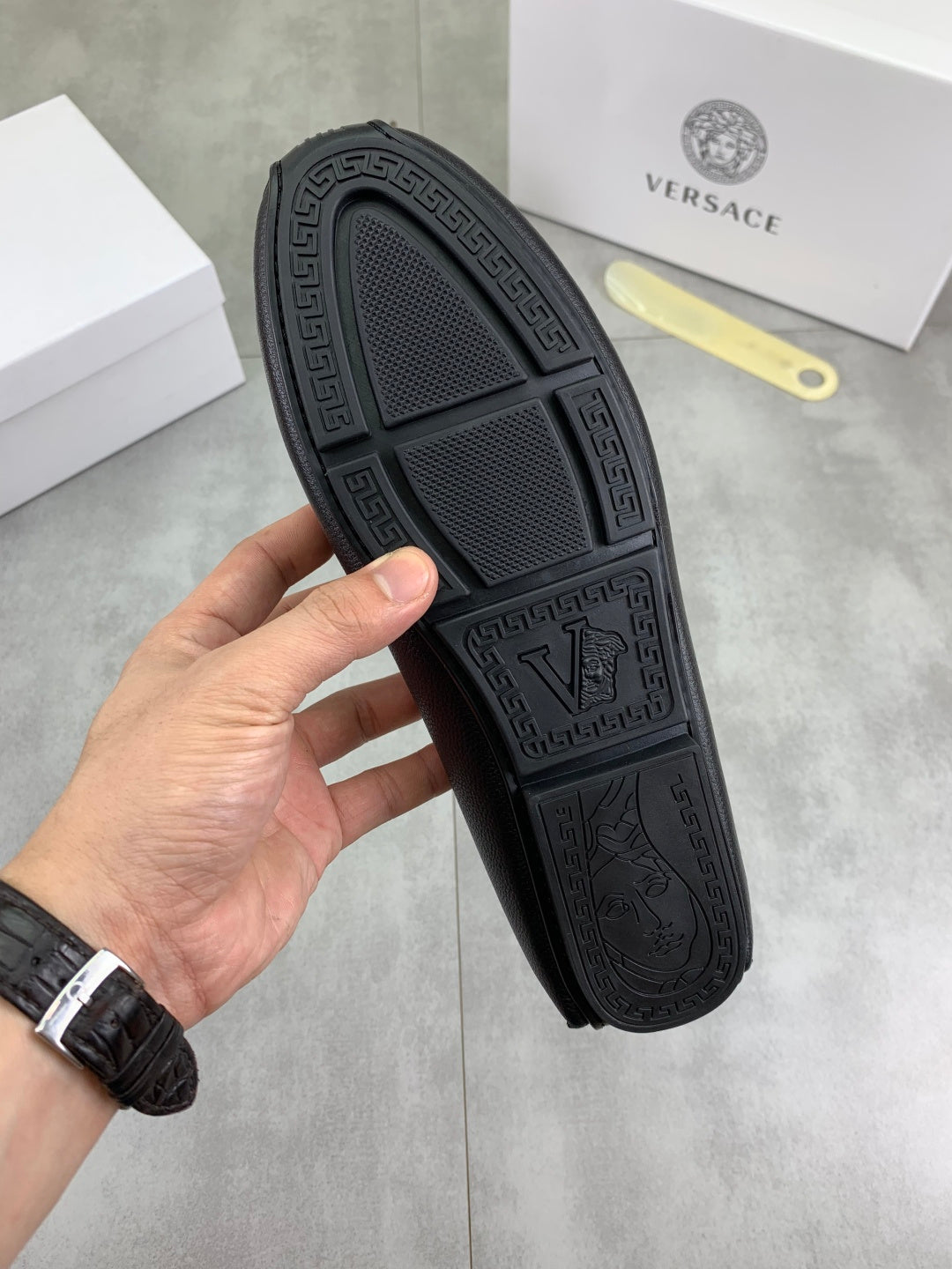 Black rubber outsole with textured designer logo pattern on loafer