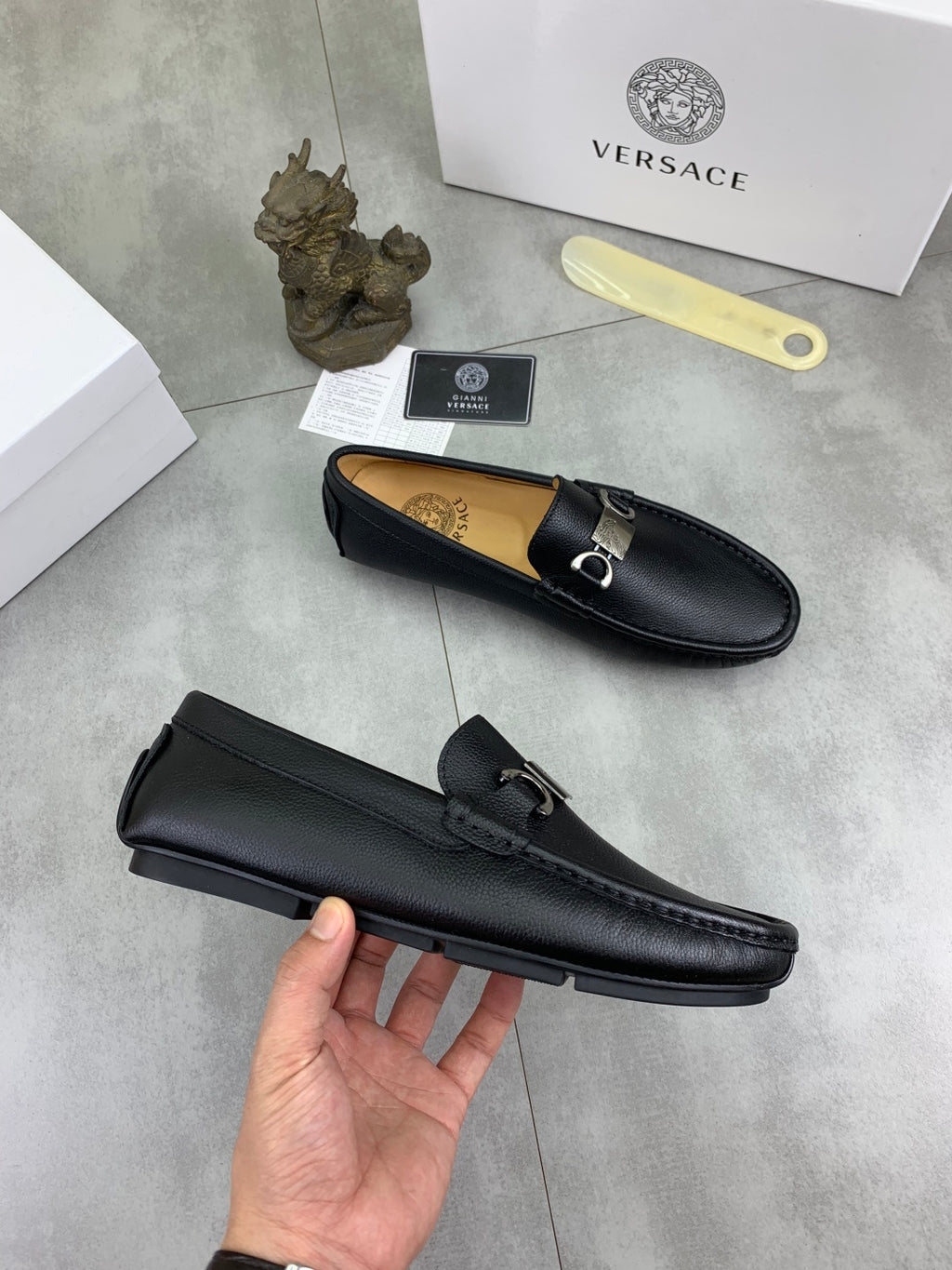 Black leather loafers, top and side views with silver buckle