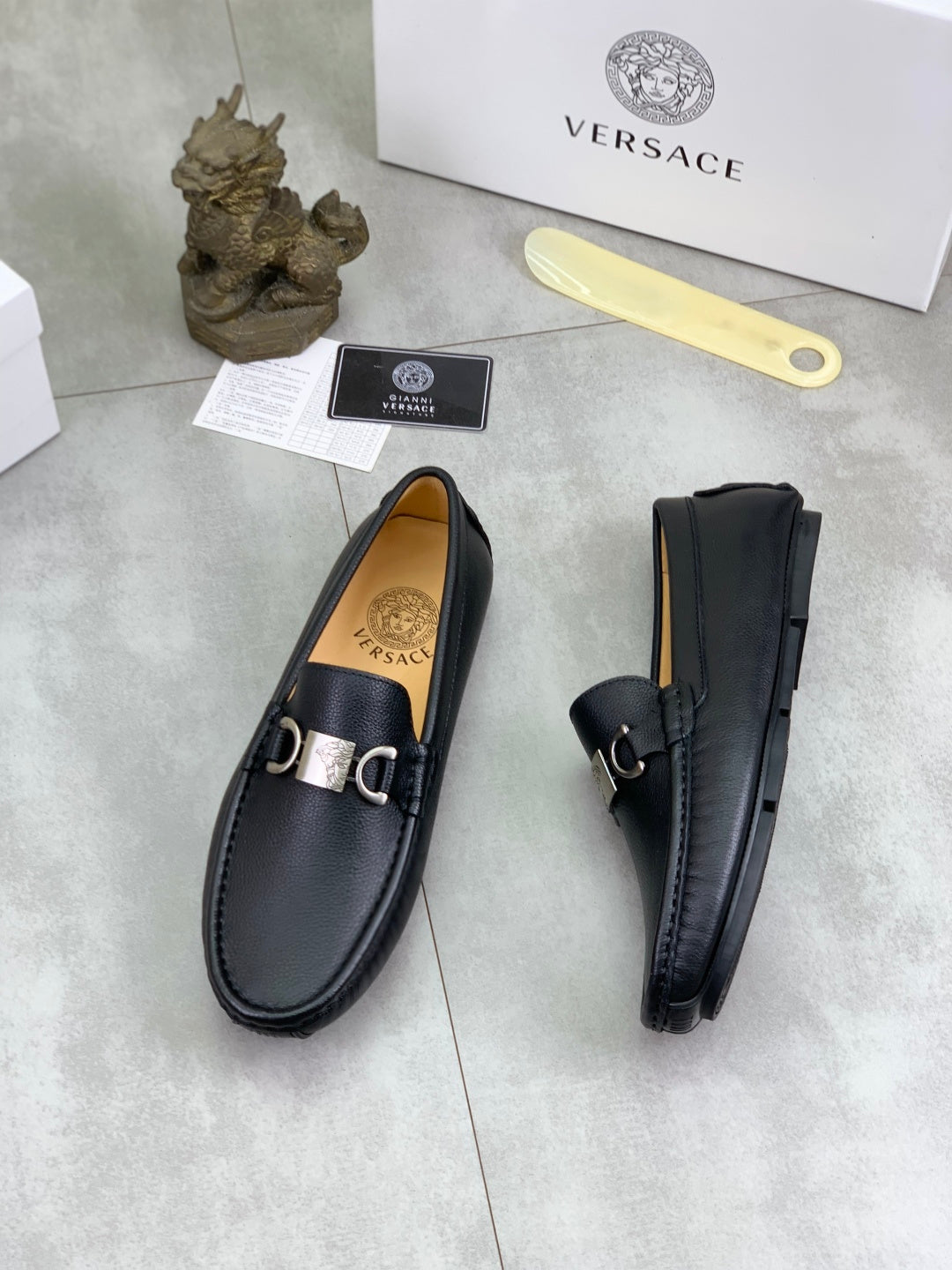 Black leather loafers, side view pair with silver buckle and stitched trim