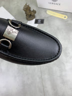 Black leather loafer upper close-up with silver buckle and stitched edge