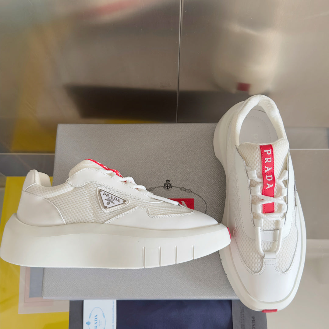Prada white sneakers on display with thick white sole and red accent laces