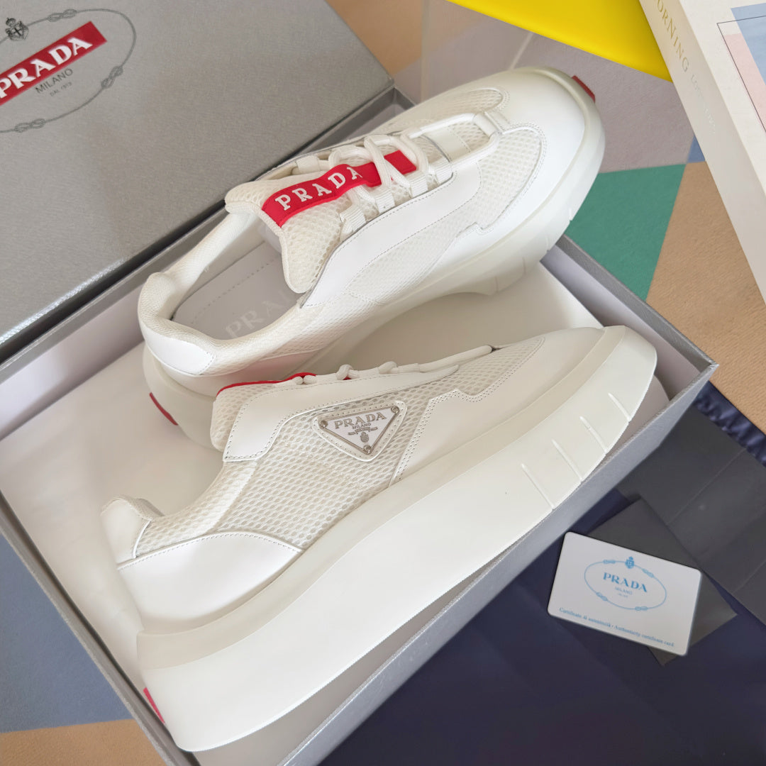 Prada white sneakers pair in box, with side logo plaque and red details