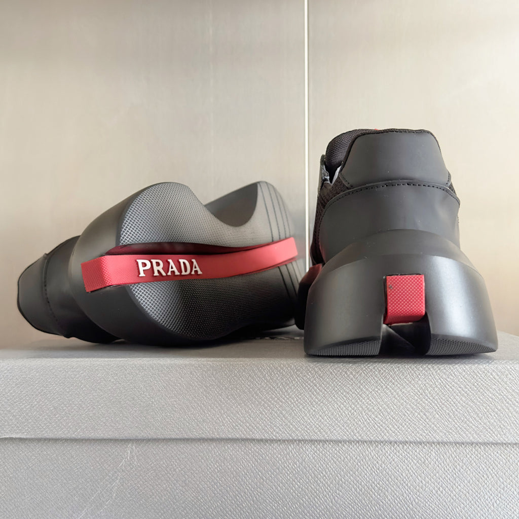 Prada unisex sneakers heel view, dark gray with red PRADA logo strip on sole