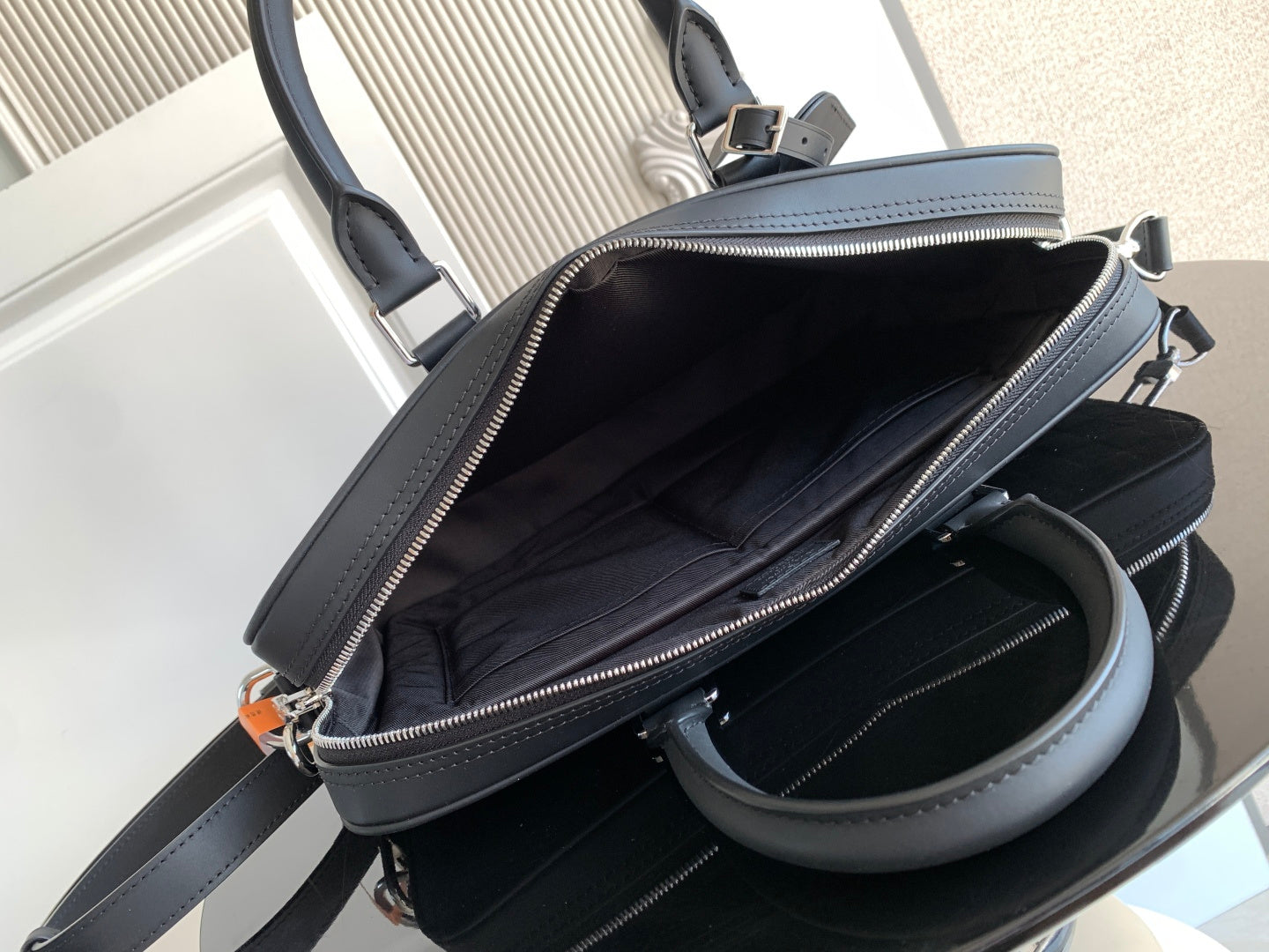 Dark handbag interior view with zip top and side pocket, shown open