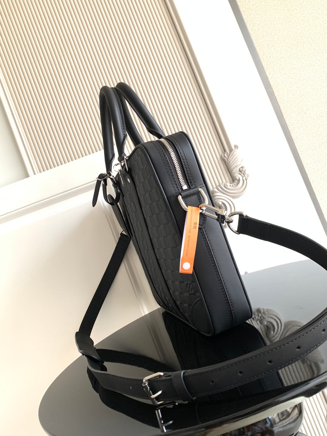 Dark woven handbag with dual handles, shoulder strap, and front zipper pocket