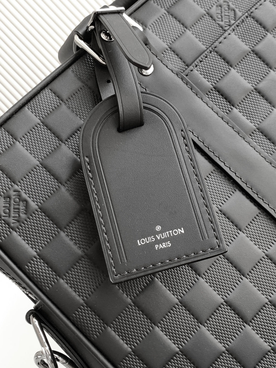 Dark woven handbag handle with logo tab and stitched trim detail