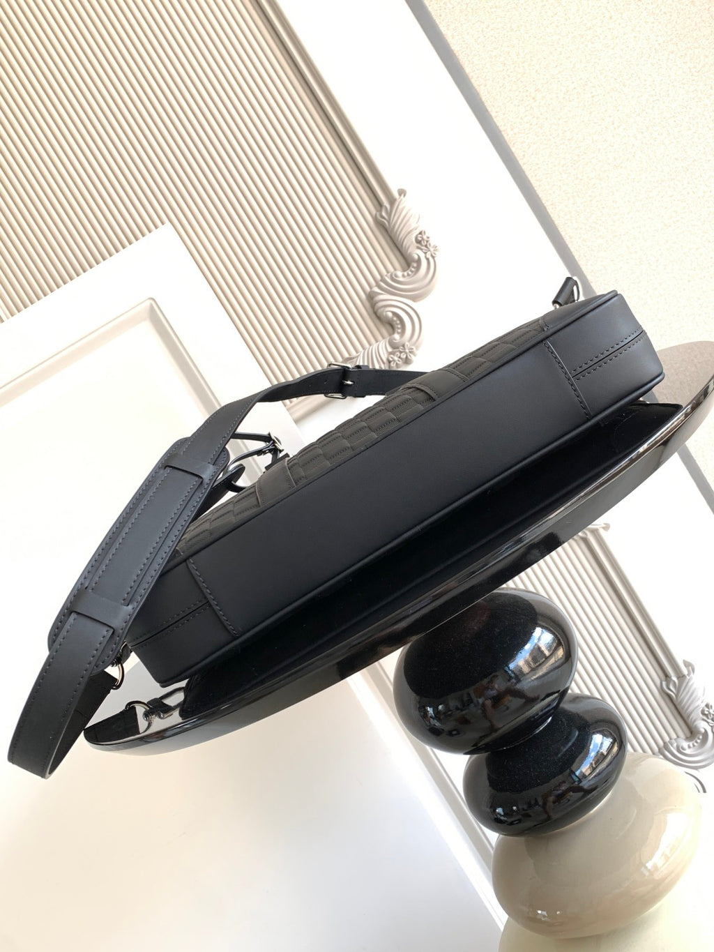 Dark shoulder handbag with strap and metal feet, side view