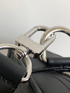 Dark handbag close-up of silver hardware and ring attachment on strap