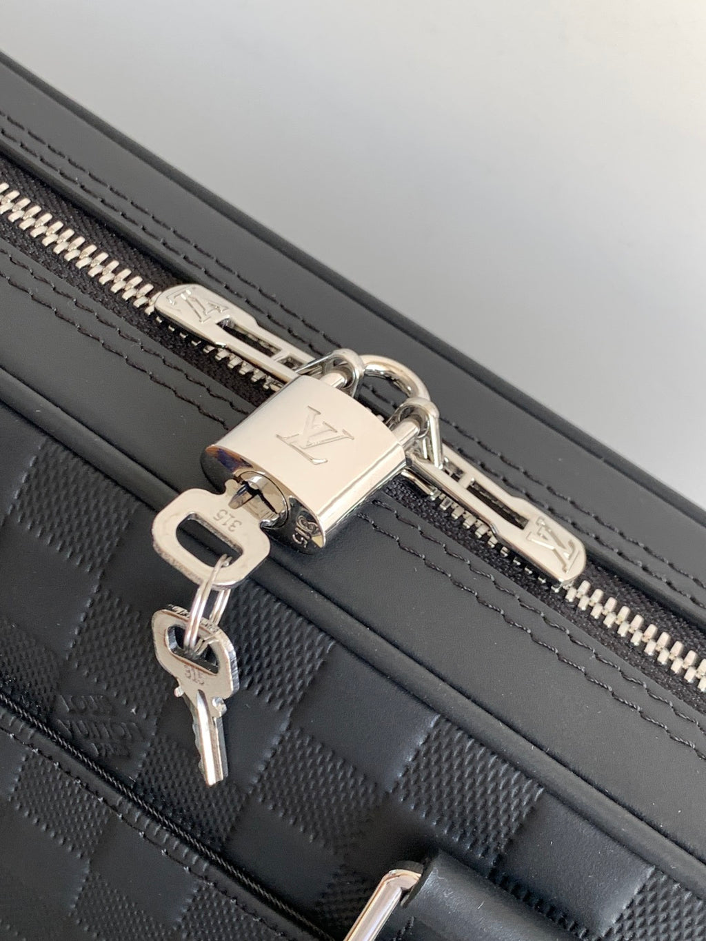 Dark woven handbag with silver zipper pulls and key ring clip