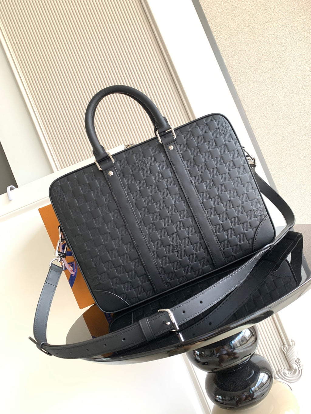 Dark woven tote-style handbag with top handles and adjustable shoulder strap