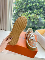 Louis Vuitton unisex sneakers, outsole view with brown tread and white-striped upper.