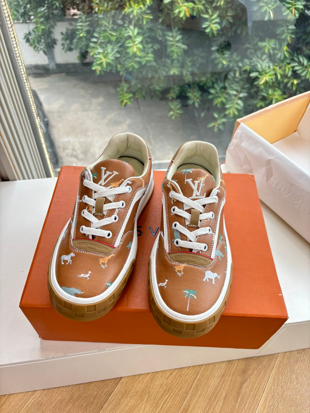 Louis Vuitton unisex sneakers, front view in box; brown leather look with white laces.