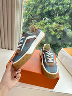 Louis Vuitton blue plaid low-top sneaker held up with white laces, gum sole on orange box.