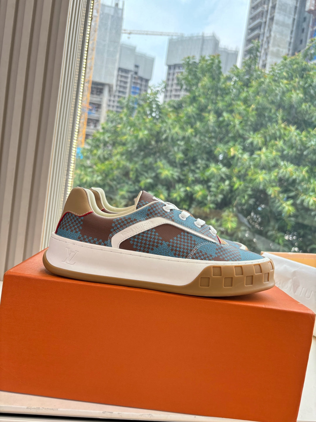 Louis Vuitton blue plaid low-top sneaker with white laces and gum sole on orange box.