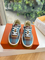 Louis Vuitton blue plaid low-top sneakers with white laces and brown trim on orange box.