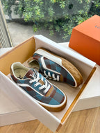Louis Vuitton blue plaid low-top sneakers with white laces in box, gum rubber sole visible.