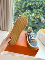 Louis Vuitton outsole of blue plaid low-top sneaker, textured gum rubber tread, held in hand.