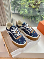 Low-top sneakers, dark blue canvas with white laces and tan rubber sole