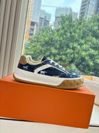 Low-top sneakers in dark blue canvas with white laces and tan sole, side profile
