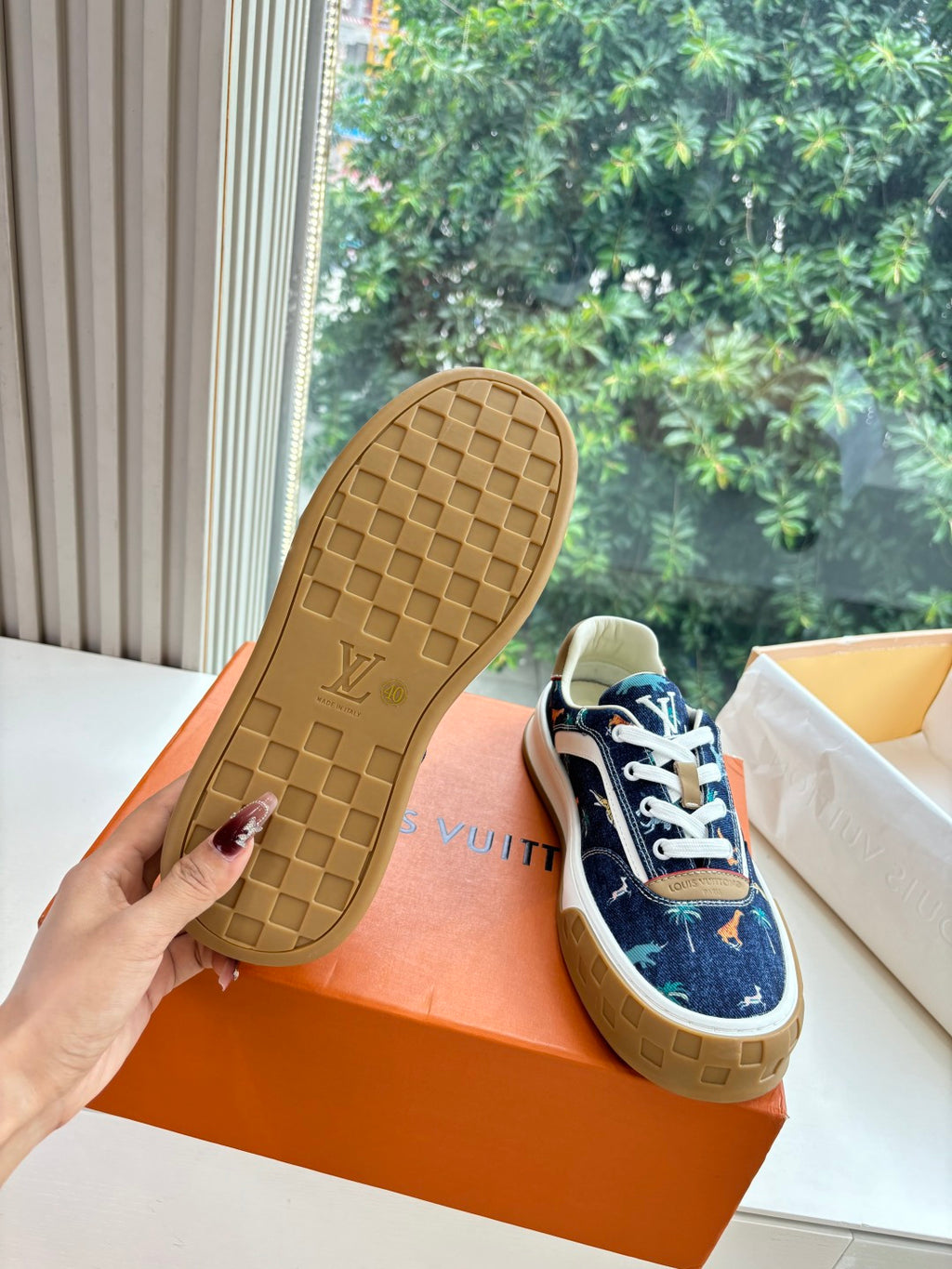 Sole view of low-top sneakers, dark blue upper with tan rubber tread