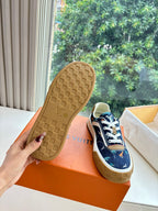 Sole view of low-top sneakers, dark blue upper with tan rubber tread