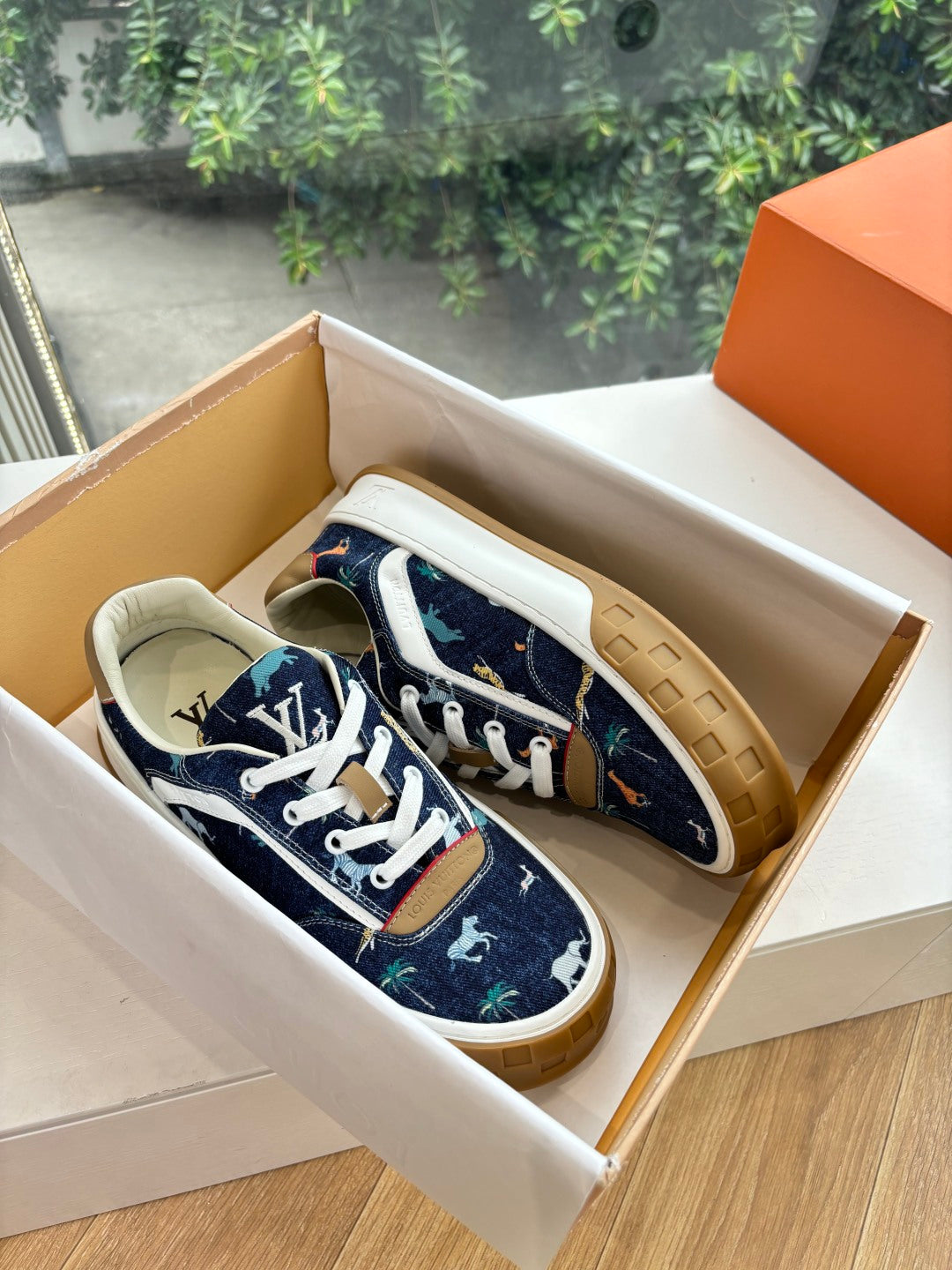 Low-top sneakers in dark blue canvas with white laces and tan sole, in shoebox
