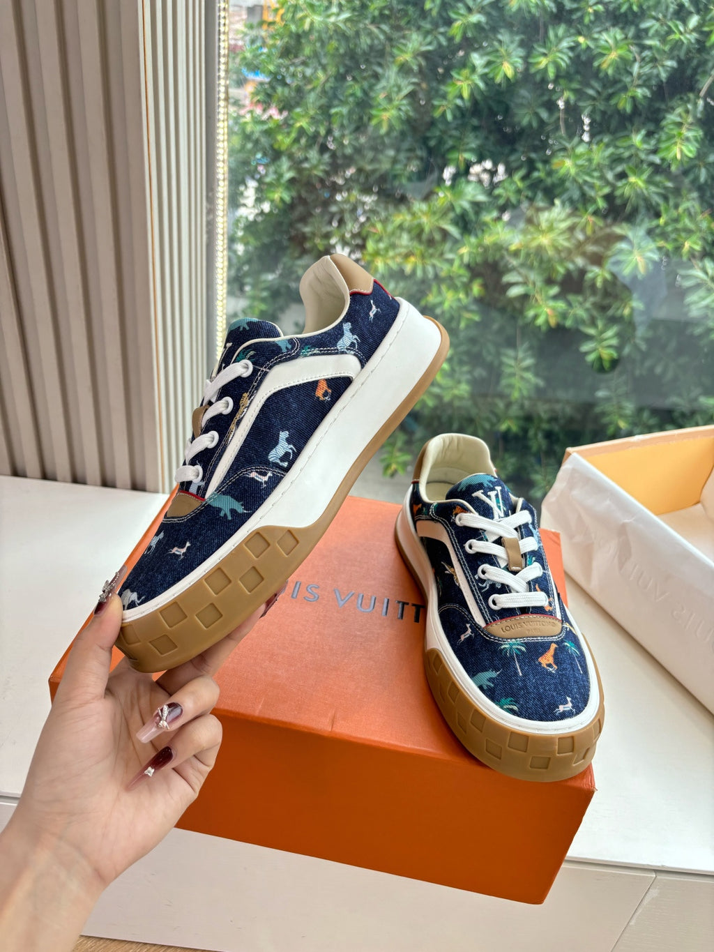 Low-top sneakers on orange box, dark blue canvas, white laces and tan rubber sole