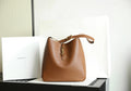 YSL bucket bag in brown leather with gold YSL charm and top handle straps