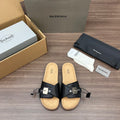 Black slide sandals with dual straps, silver buckles, and cork-textured footbed