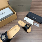 Black slide sandals with metal buckle strap and cushioned cork footbed