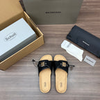 Black slide sandals with adjustable buckle straps and cork-look footbed