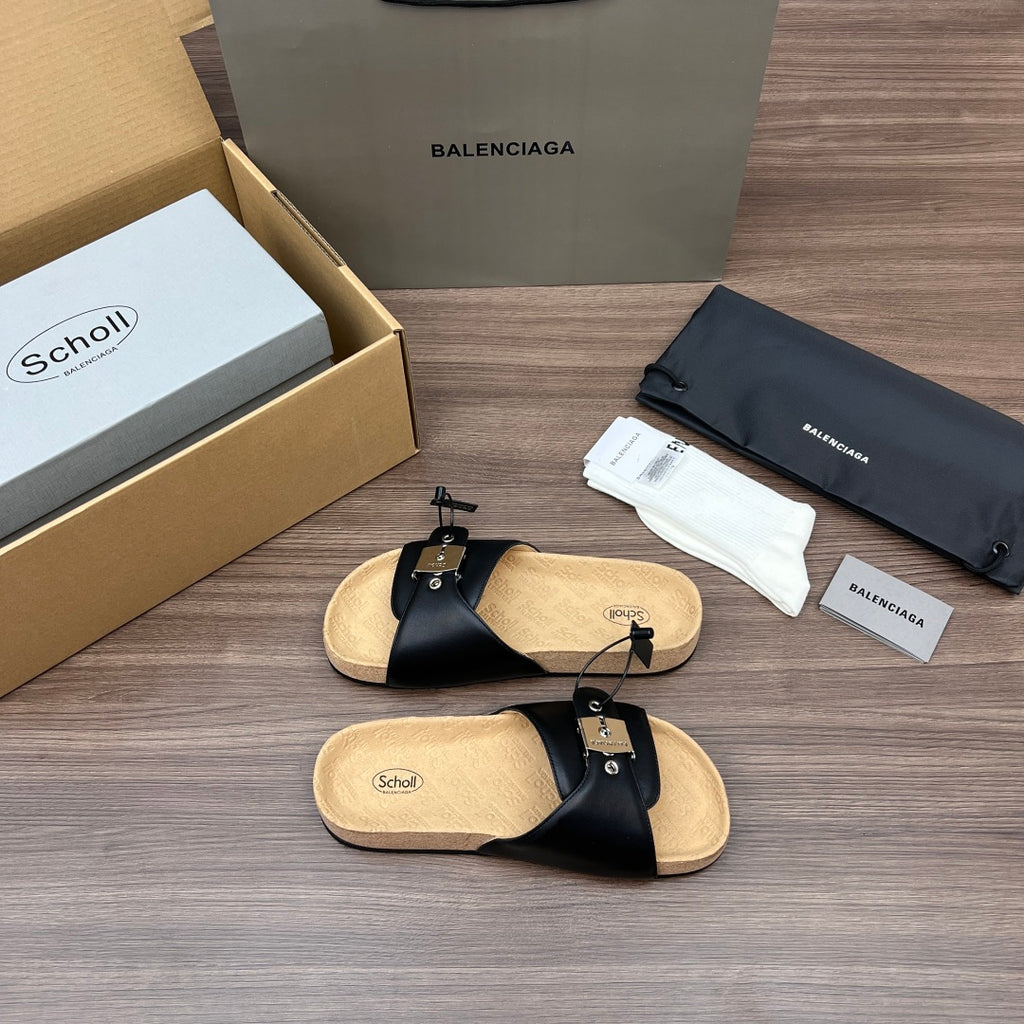 Pair of black slide sandals with cross straps, silver hardware, and light cork footbed