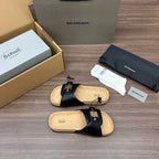 Pair of black slide sandals with cross straps, silver hardware, and light cork footbed