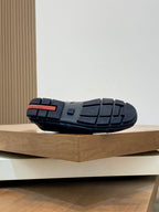 Black Prada unisex sneaker outsole view, tread pattern with red accent