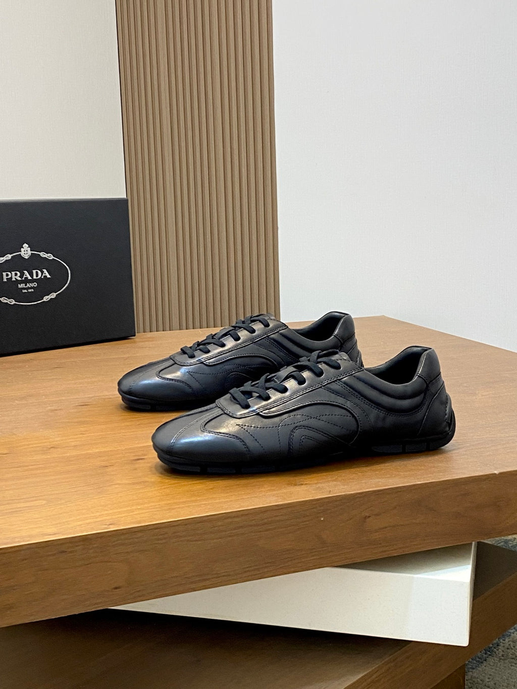 Black Prada unisex sneakers pair, lace-up front with textured leather panels
