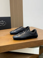 Black Prada unisex sneakers pair, lace-up front with textured leather panels