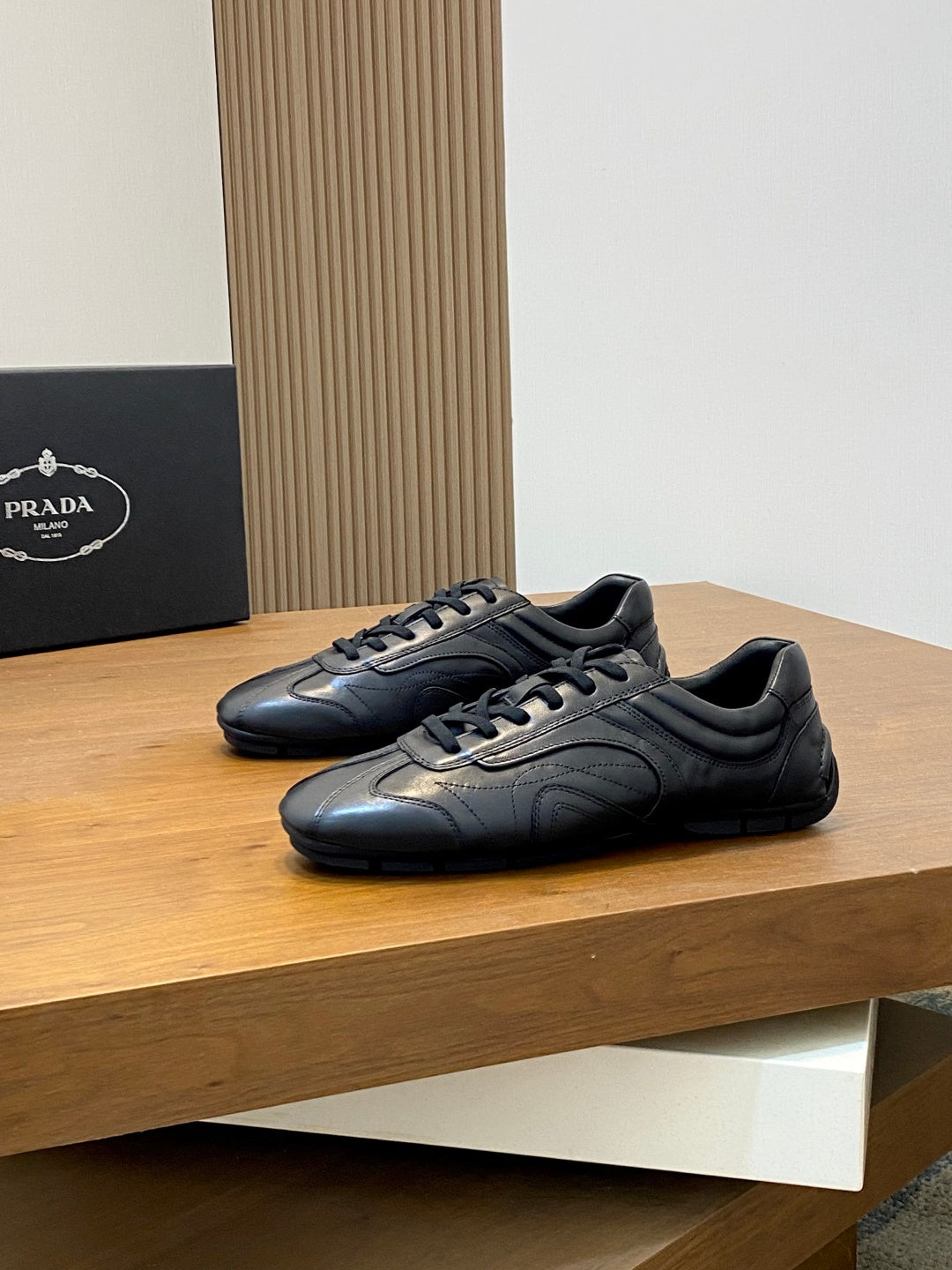 Black Prada unisex sneakers pair, lace-up front with textured leather panels