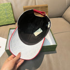 Gucci cap in black with GG-pattern sides, red trim edge, and adjustable strap.